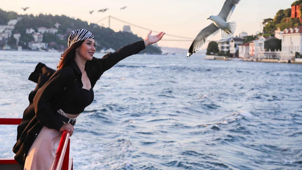 Sightseeing boat passing waterfront yali houses on the Bosphorus in Istanbul, Türkiye