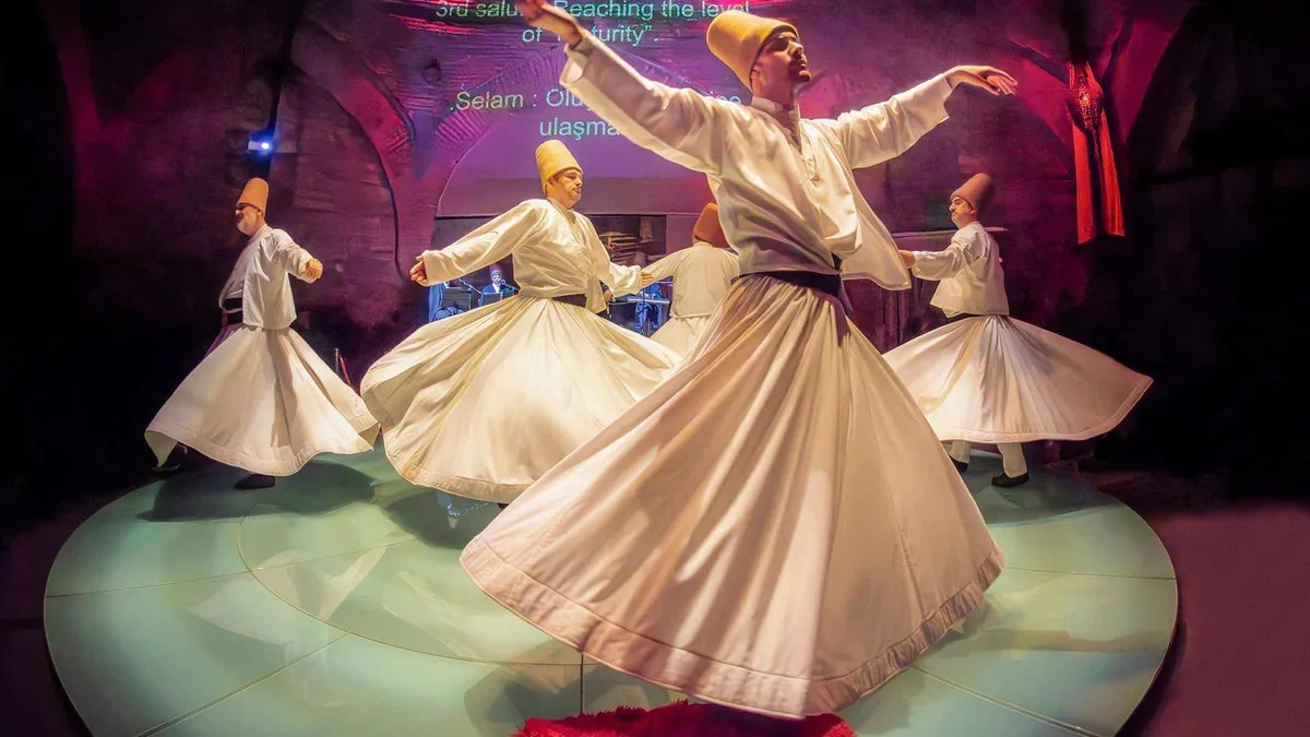 Whirling dervishes in white skirts turning under stage light in Istanbul, Türkiye